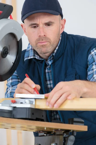 Uomo misura tavole di legno con nastro e matita — Foto Stock