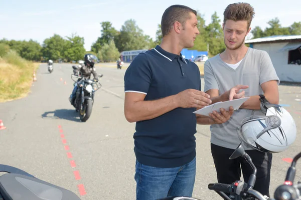 Motorbike instructor showing a paper to the student — Stock Photo, Image