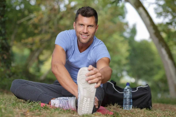 Mannen stretching innan du kör på en skogsstig — Stockfoto