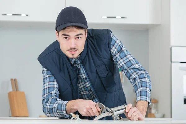 Giovane artigiano che ripara rubinetto in cucina — Foto Stock