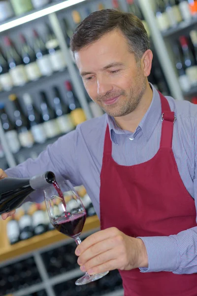 Weinhändler schenkt Glas Rot ein — Stockfoto