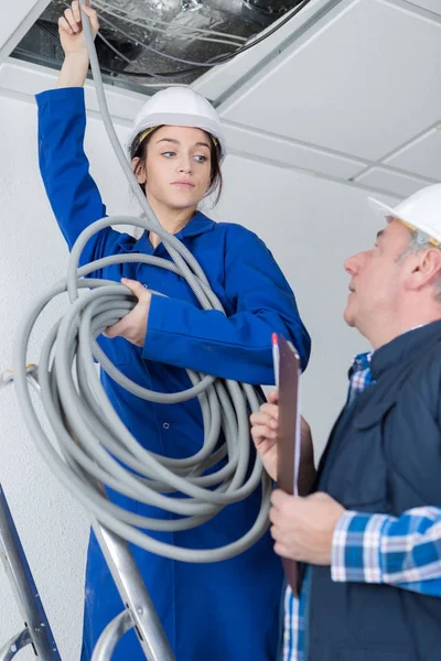 Jonge vrouwelijke elektricien met mentor — Stockfoto