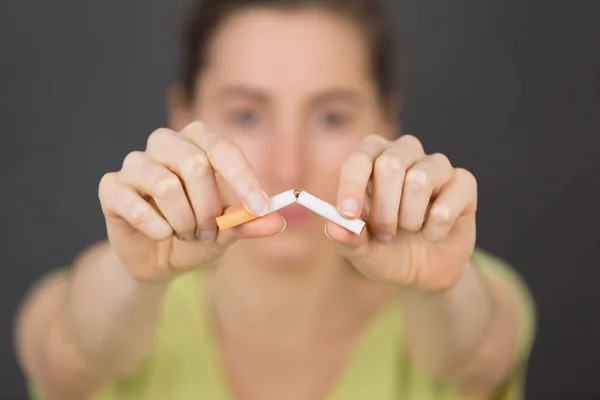 Una mujer rompiendo un cigarrillo por la mitad — Foto de Stock