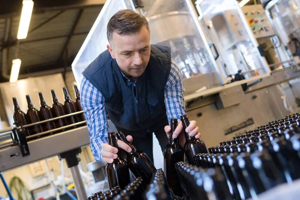 Fabrika işçisi konveyör taşıma şarap şişeleri ile çalışma — Stok fotoğraf