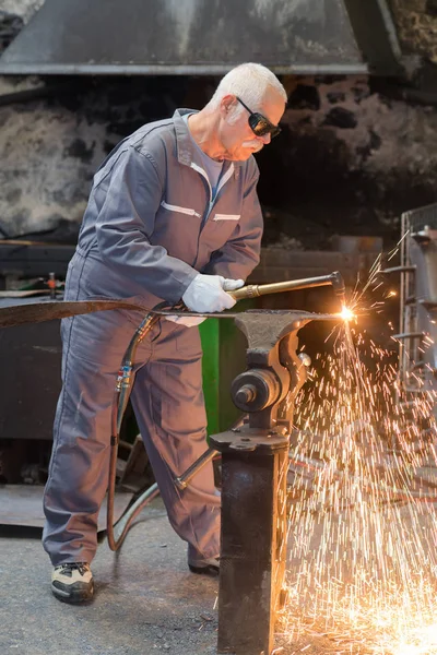 Senior worker in protective mask welding steel railings outdoors — Stock Photo, Image