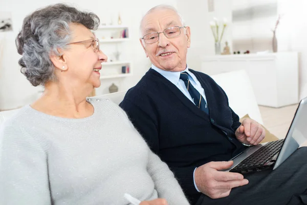 Συνταξιούχο ζευγάρι χρησιμοποιώντας φορητό υπολογιστή στο σπίτι — Φωτογραφία Αρχείου