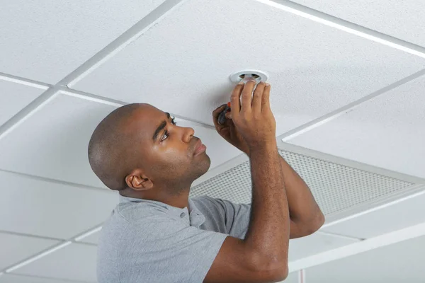 Man fitting spotlight to ceiling — Stock Photo, Image
