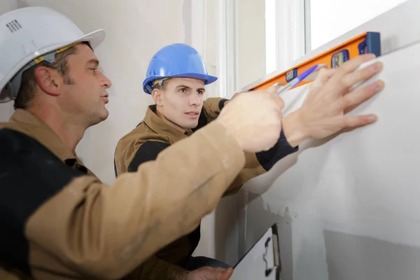 Unga byggnadsarbetare installerar fönster i hus — Stockfoto