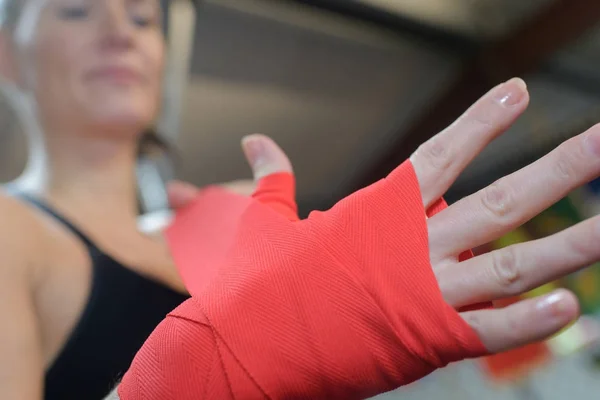 Woman is wrapping hands with red boxing hand wraps — Stock Photo, Image