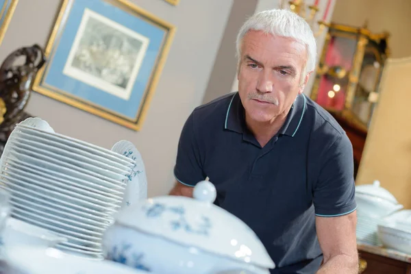 Homem olhando para louças de porcelana — Fotografia de Stock