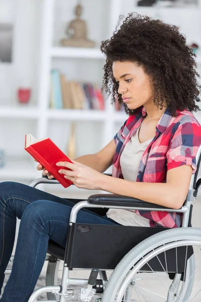 Jovem mulher ler livro em cadeira de rodas — Fotografia de Stock