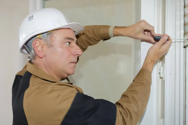 A man fixes basis blinds to frame the window — Stock Photo, Image