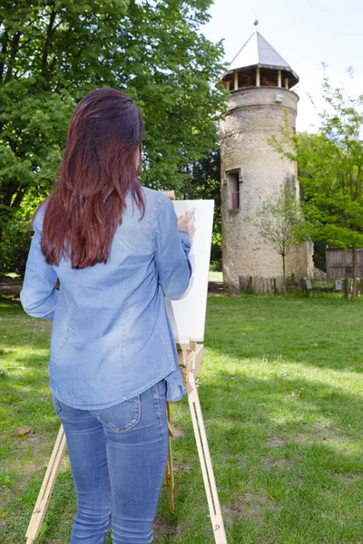 Young woman painting on canvas outside — Stock Photo, Image
