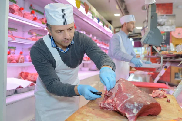 Carnicero rebanando una carne — Foto de Stock