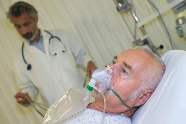 Ärzte helfen Patienten mit Sauerstoffmaske im Krankenhauszimmer — Stockfoto