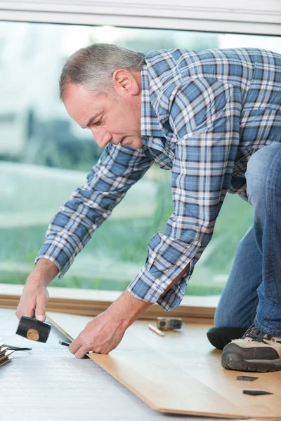 Instalador de piso usando um martelo — Fotografia de Stock