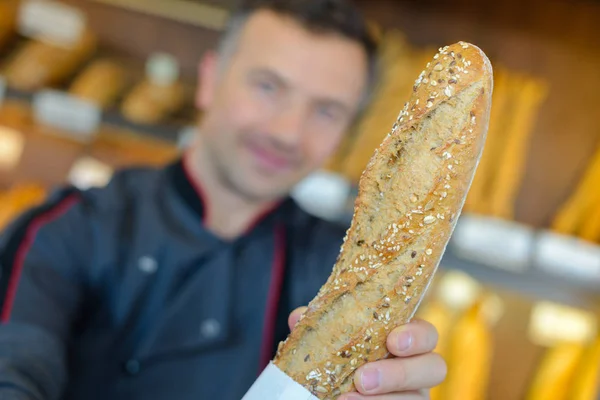 パン屋さんの店主は彼のパンの生産を誇り、します。 — ストック写真
