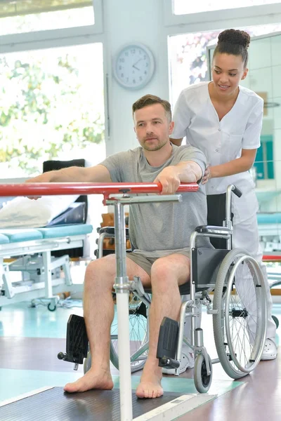 Fizjoterapeuta, pomagając człowiek na wózku inwalidzkim ćwiczeń — Zdjęcie stockowe