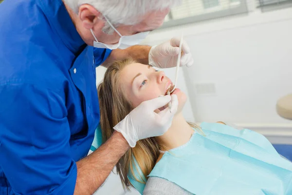 Dentista revisando los dientes de los pacientes con un espejo y una sonda — Foto de Stock