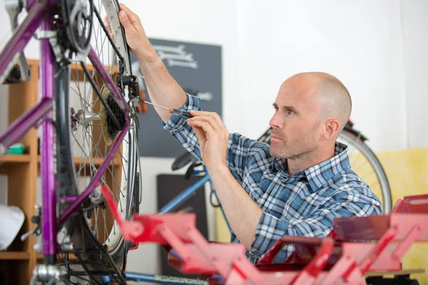 Un homme réparant un vélo dans son atelier — Photo