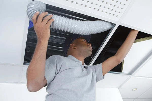 Man fitting ventilation hose into roofspace — Stock Photo, Image