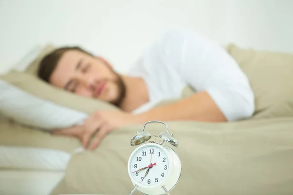 Clock on a table man sleeping in the background — Stock Photo, Image