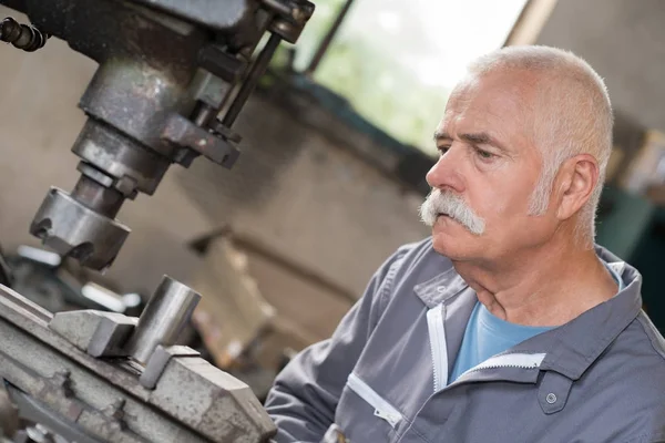 Äldre arbetare klockor bearbetning av detalj på fräsmaskin — Stockfoto