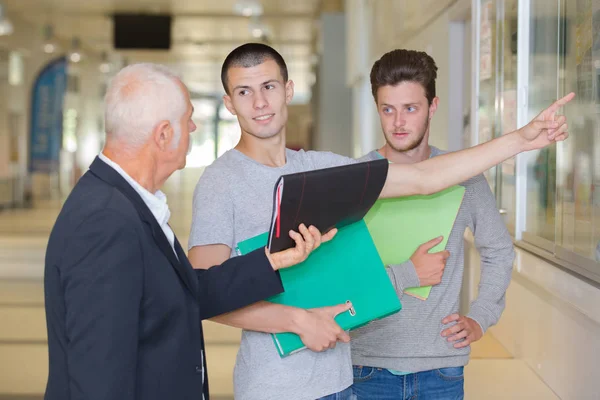 Middelbare scholieren en leraar wandelen langs gang — Stockfoto