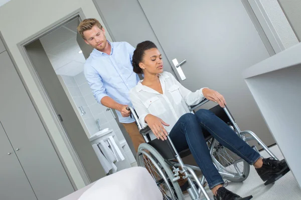 Jonge mooie vrouw in rolstoel geduwd door haar vriendje — Stockfoto
