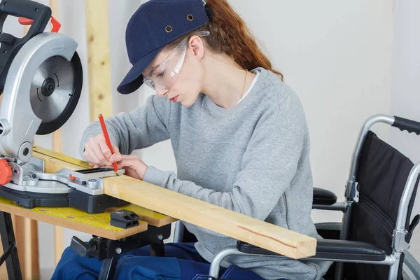 Vrouwelijke timmerman op rolstoel met behulp van een cirkelzaag — Stockfoto