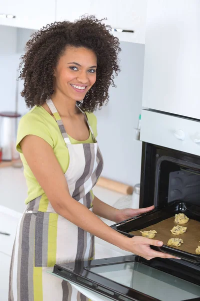 Женщина кладет еду в духовку — стоковое фото