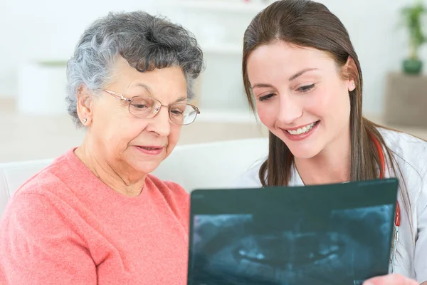 Старша жінка, що переглядає рентгенівські результати з лікарем — стокове фото
