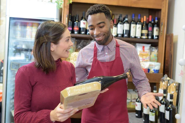 Vendedor dando consejo mujer en la compra de botella de vino tinto — Foto de Stock