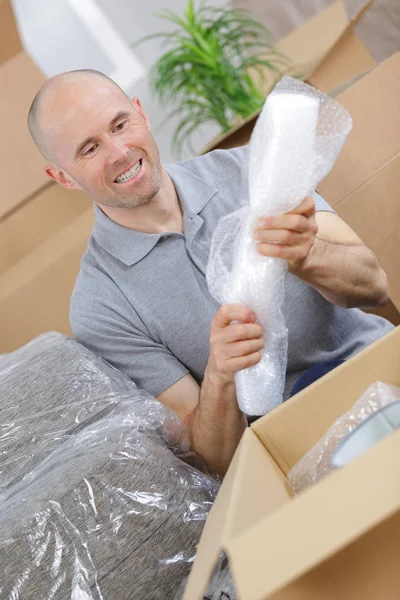 Happy man moving in and opening carton box — Stock Photo, Image