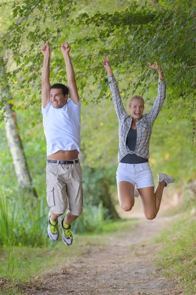 Um casal pulando depois de completar sua caminhada ao ar livre — Fotografia de Stock