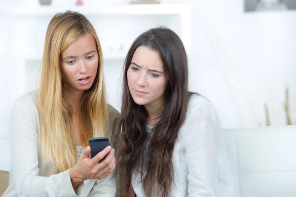 Twee mooie meisjes verrast tijdens het kijken naar de telefoon — Stockfoto