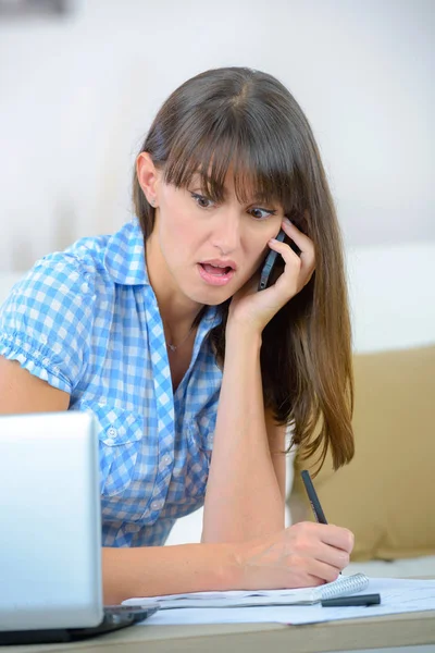 Donna d'affari scioccato utilizzando un computer portatile e parlando al telefono — Foto Stock