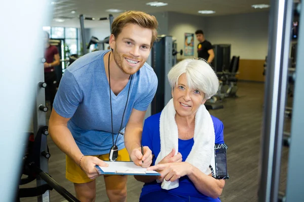 Unga tränare arbetar med äldre dam på gymmet — Stockfoto