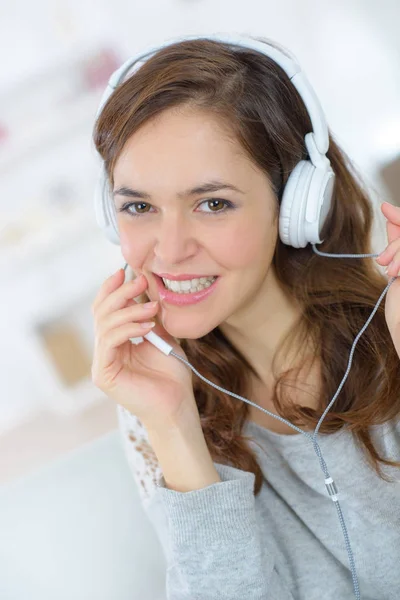 Jovem sorrindo mulher relaxante e ouvir música com fones de ouvido — Fotografia de Stock