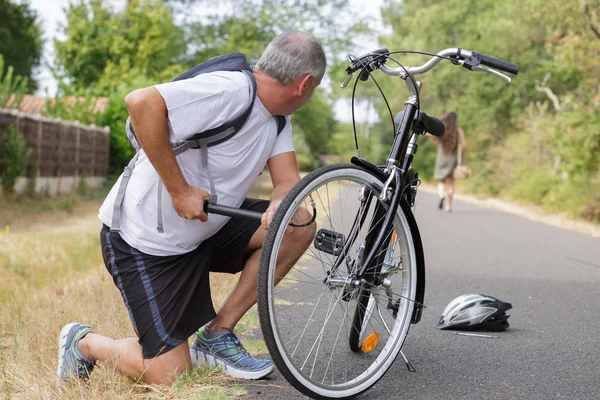 Homem bomba até a roda de bicicleta ao ar livre — Fotografia de Stock