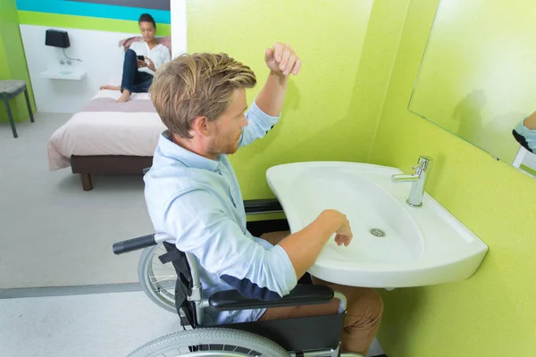 Hombre discapacitado en el lavabo en la habitación de hotel —  Fotos de Stock