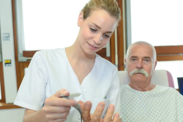 Kvinnlig sjuksköterska tar hand om en gammal patient — Stockfoto