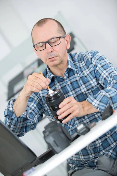Man dusting camera lens — Stock Photo, Image