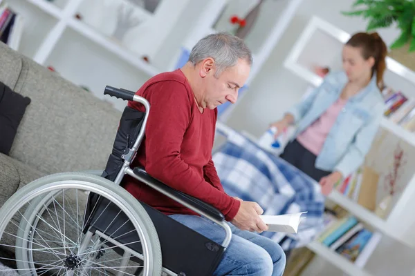 Mann im Rollstuhl und Krankenschwester helfen beim Bügeln — Stockfoto