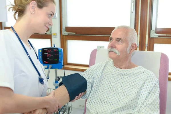 Beautiful female doctoris testing patients blood pressure — Stock Photo, Image