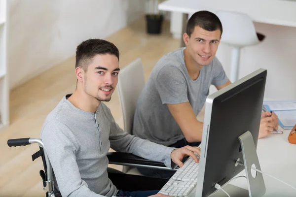 Estudiante en silla de ruedas trabajando con un compañero de clase —  Fotos de Stock