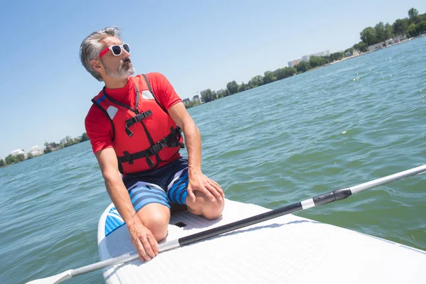 Mature attractive rider contemplating nature sitting on paddle board — Stock Photo, Image