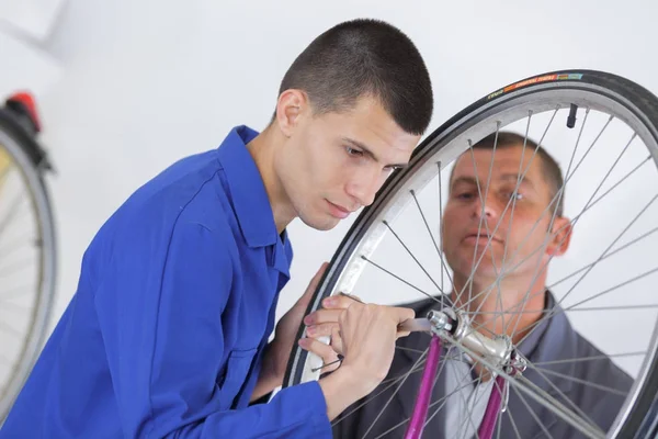 Genç adam onarmak bisiklet tekerleği — Stok fotoğraf