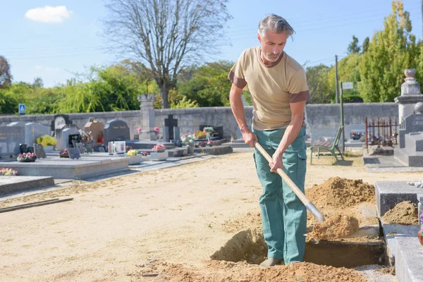 Man shovelling sand into grave — Stock Photo, Image