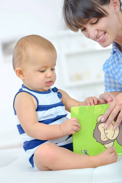 Mulher lançando livro de fotos com bebê — Fotografia de Stock